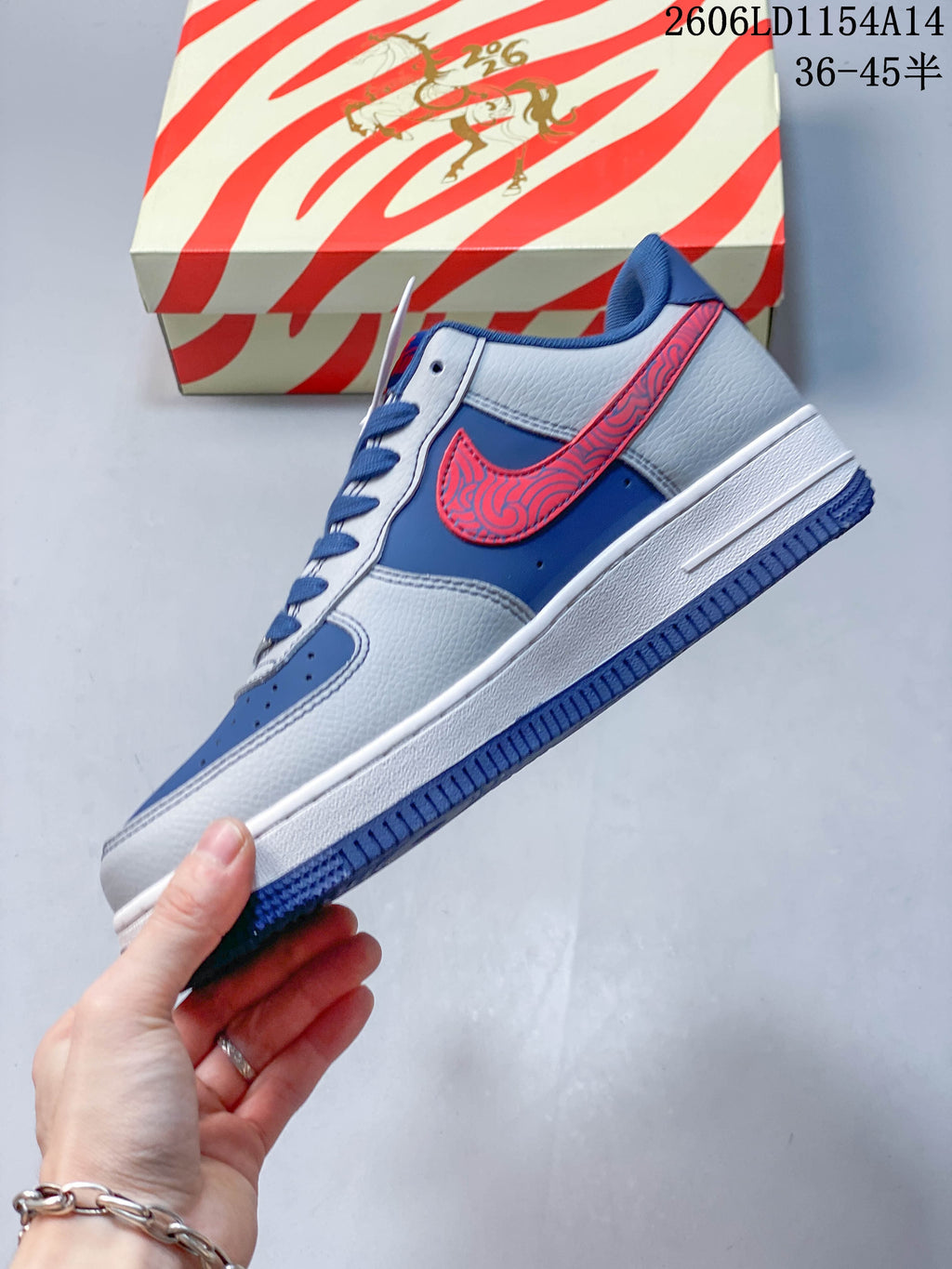 Side view showing the blue and grey upper and red patterned side logo on a Nike Air Force 1 ’07 Low sneaker.
