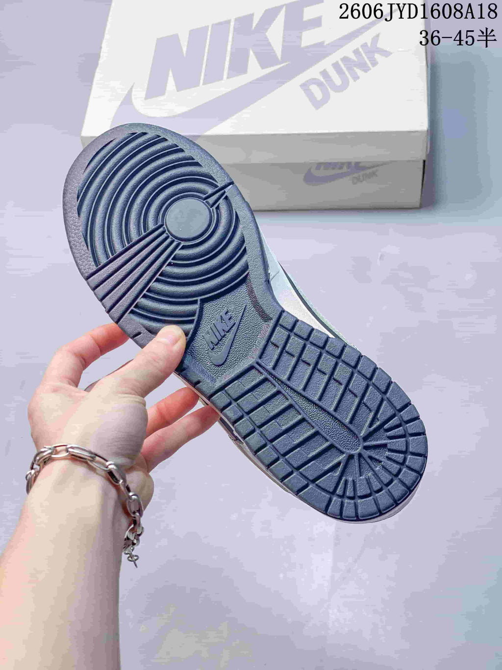 View of the dark outsole on a Nike Dunk sneaker with a Nike Dunk box in the background