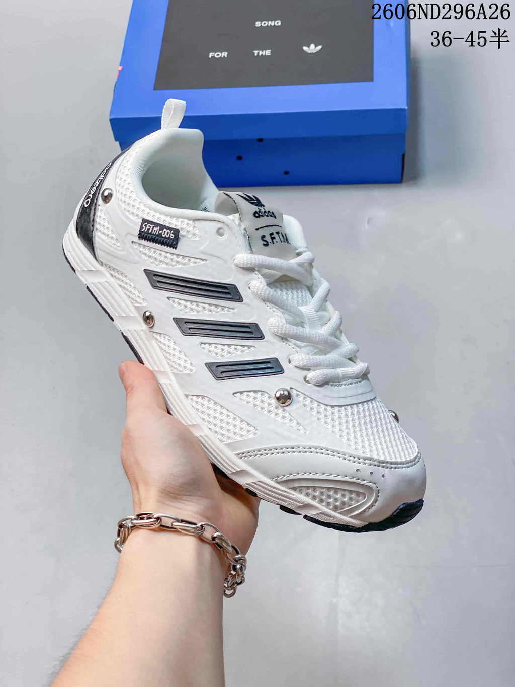 Side view of a white S.F.T.M. low-top sneaker with dark accents