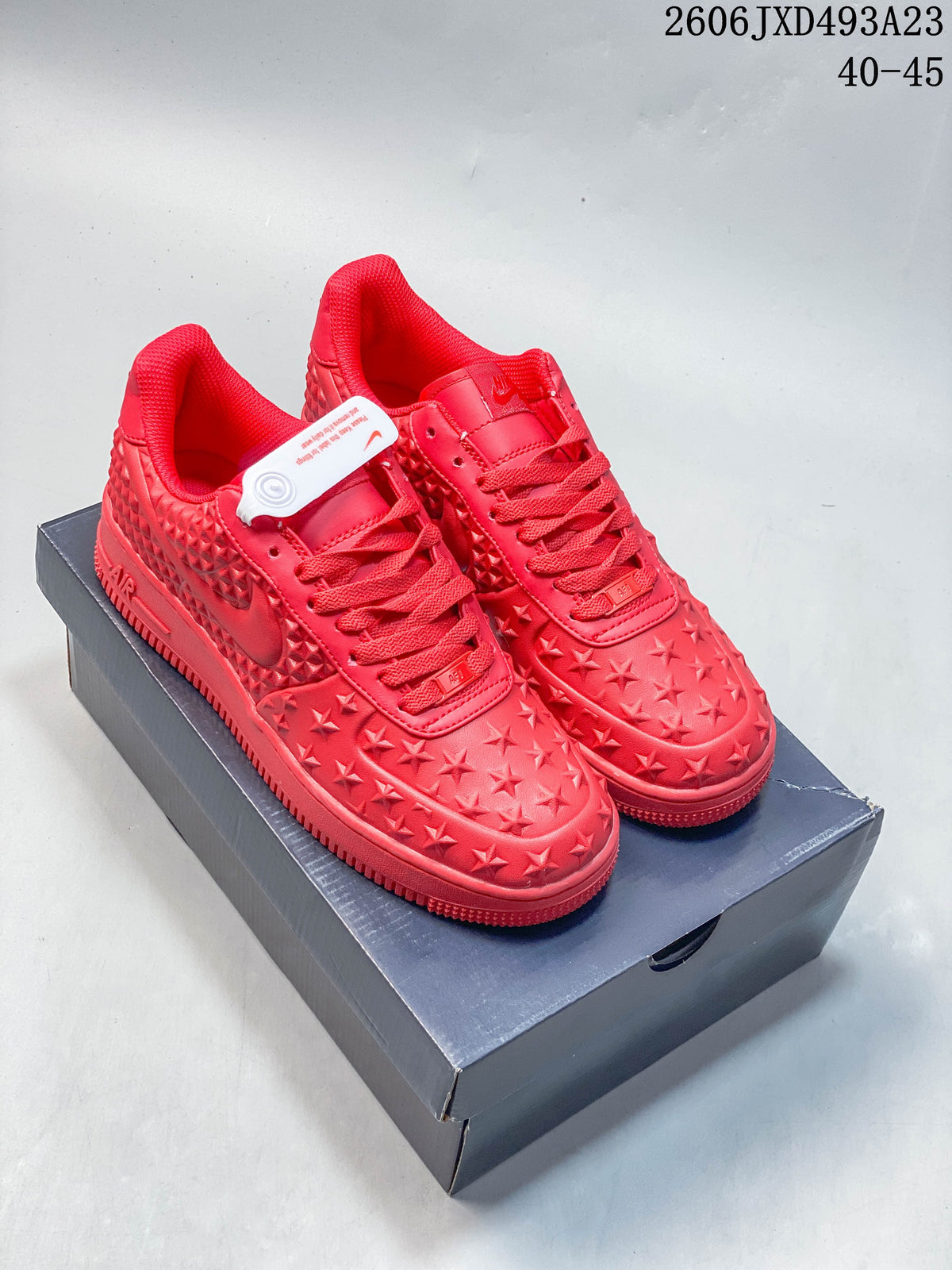 Pair of red Nike Air Force 1 Low-style sneakers with raised star details and diamond-textured side panels