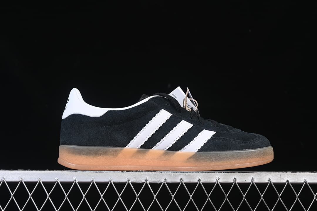 Side profile of a black sneaker with white stripes and a gum-colored sole.