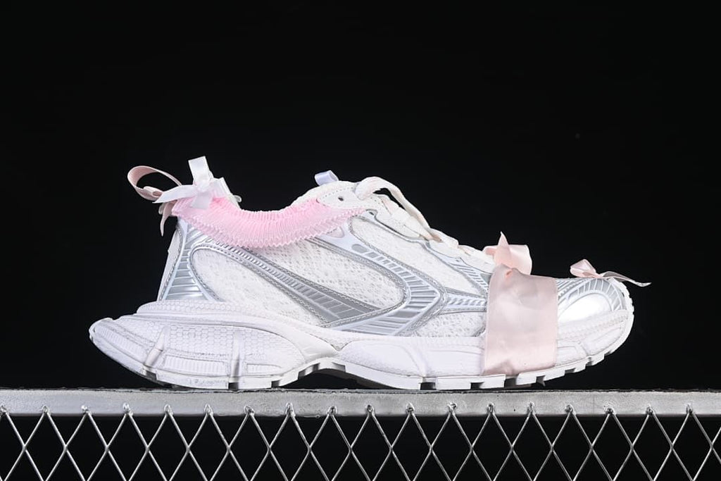Side profile of the sneaker with its chunky sole and pink ribbon accents.