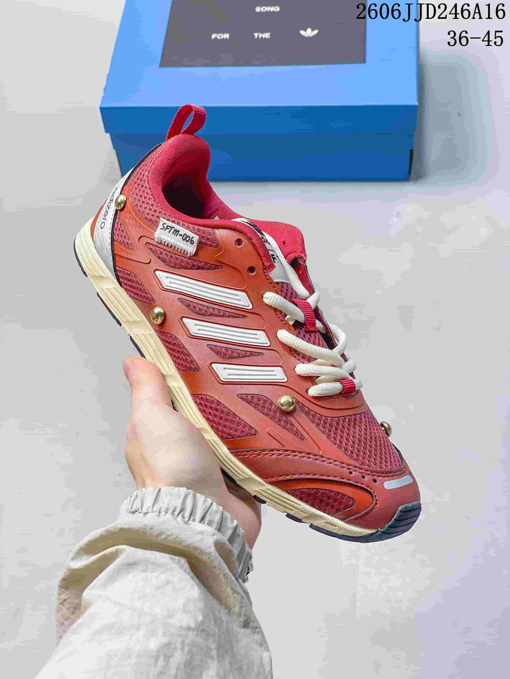 Side view of a red and coral Adizero PR SFTM-006 sneaker
