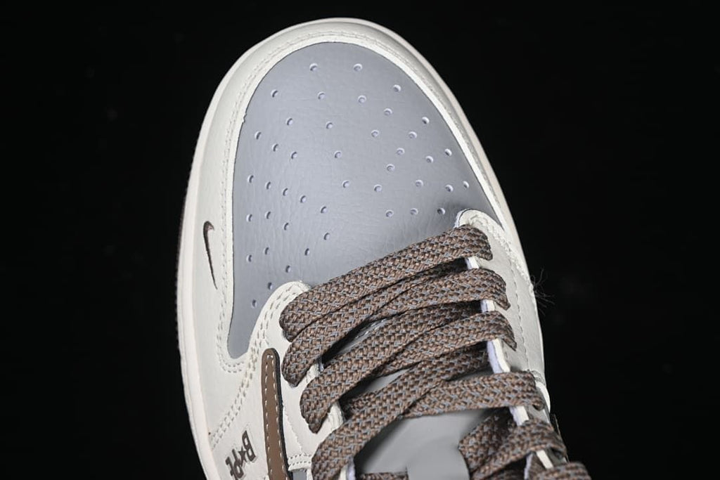 Top-down close-up of perforated gray toe panel and brown laces.