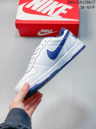 Side profile highlighting the white upper, blue Swoosh, layered panels, and blue outsole edge.