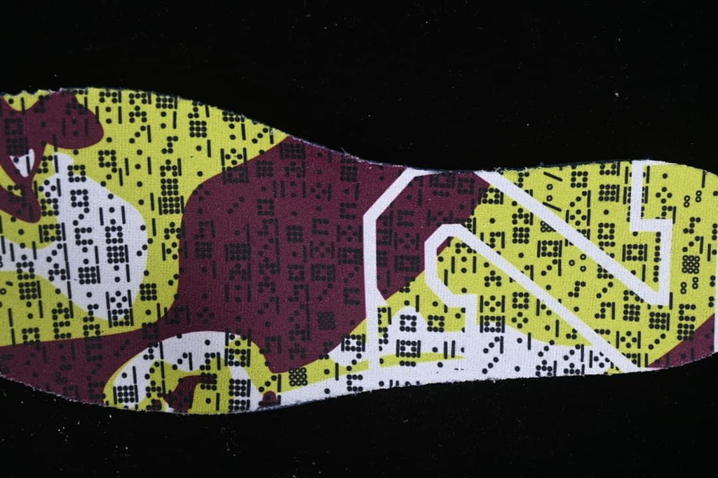 Close-up of a patterned shoe insert with yellow-green, burgundy, and white graphics.