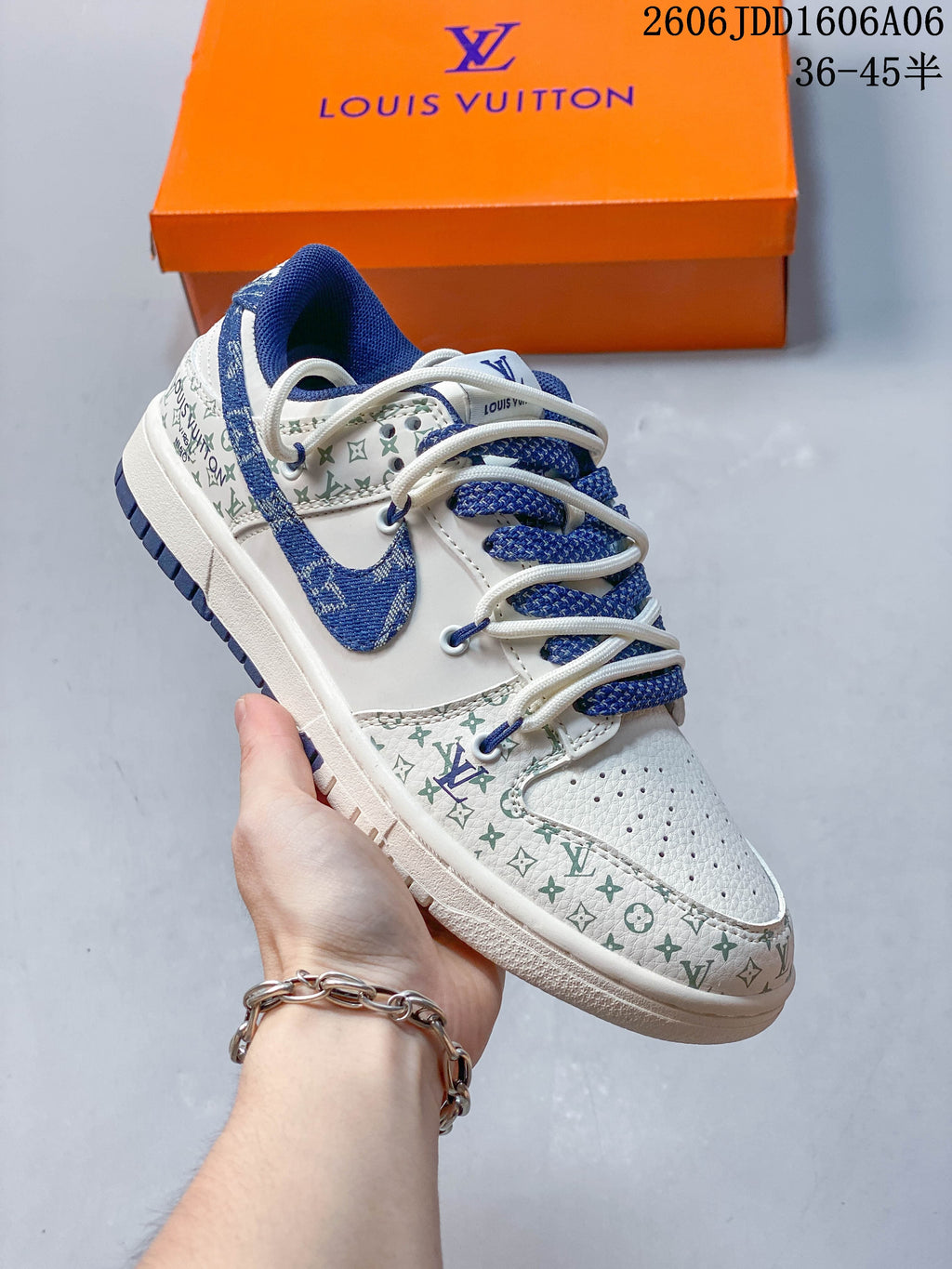 Cream low-top sneaker with green patterned panels, blue accents, and layered laces.