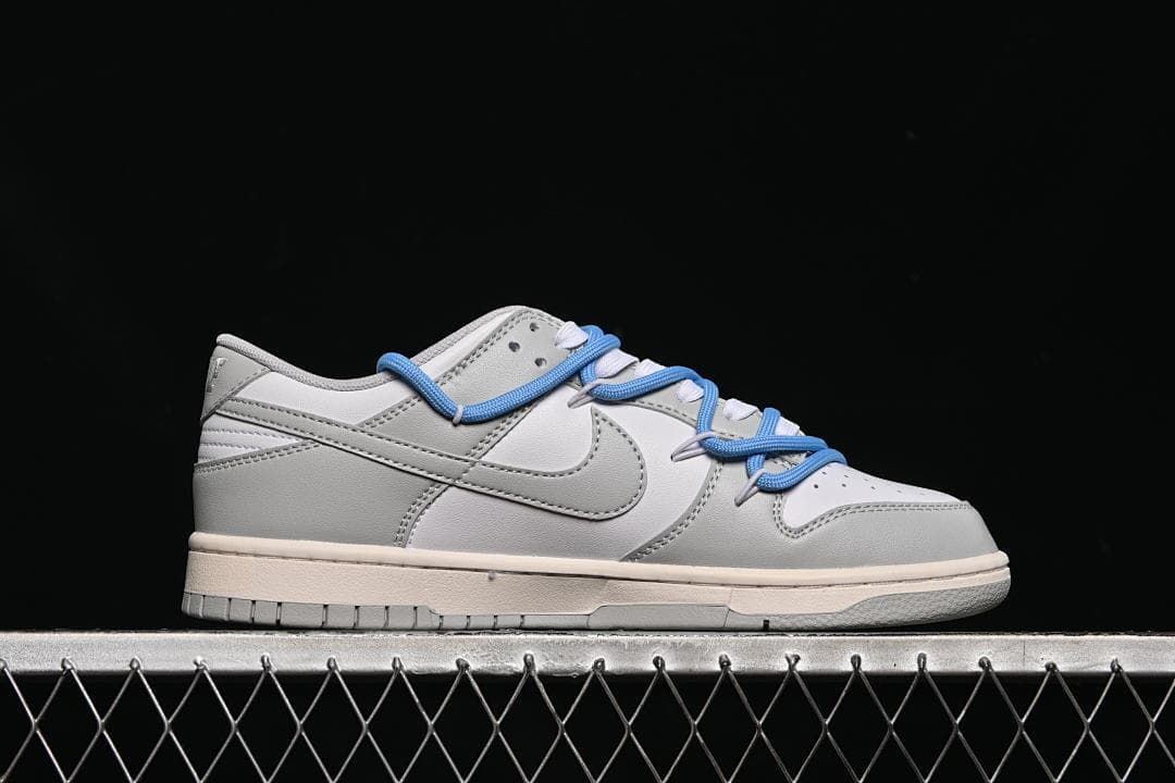 Side profile of the low-top sneaker with white and grey panels and blue laces