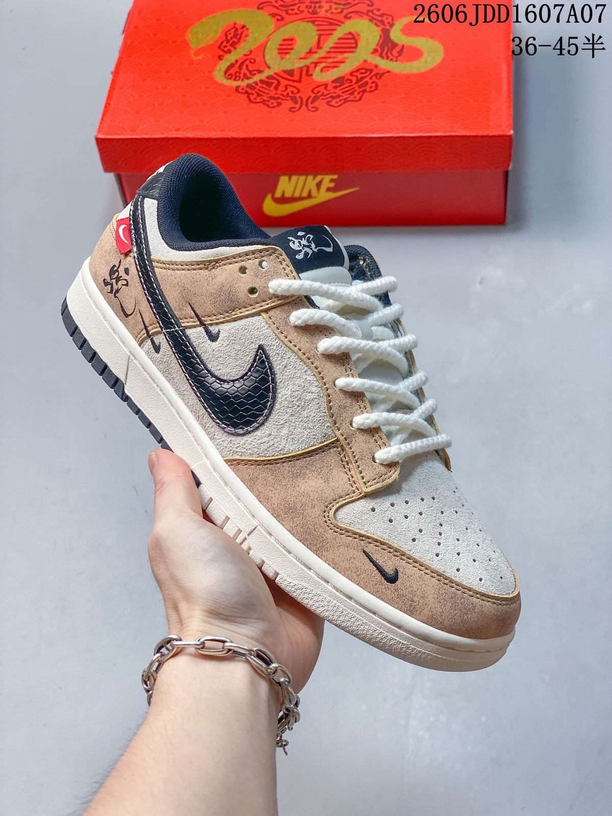 Angled view of a beige, cream, and navy Nike SB Dunk Low with white laces and decorative side details; image overlay states sizes 36–45.5.