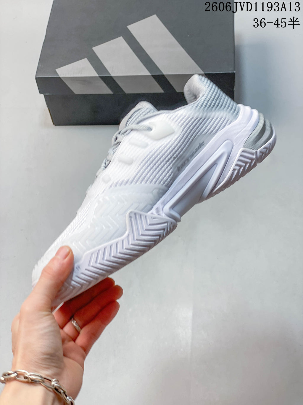 Side view of a white and silver Adidas Barricade tennis shoe