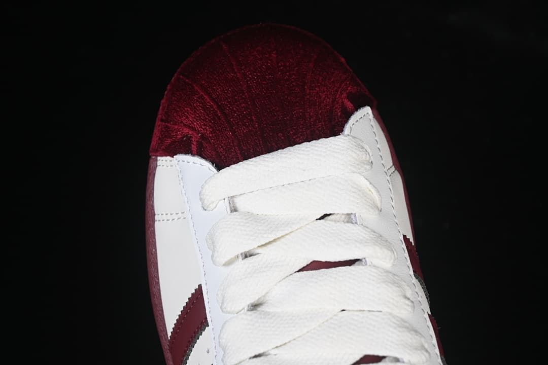 Top-down close-up of the burgundy textured toe and white laces.