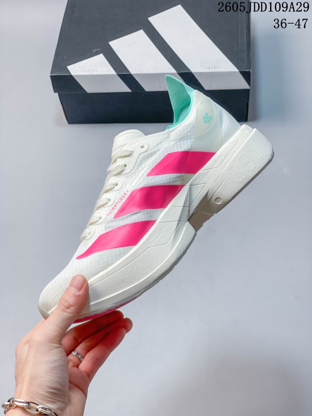 Side and heel view of the white sneaker showing pink accents, teal collar lining, and the raised sole.
