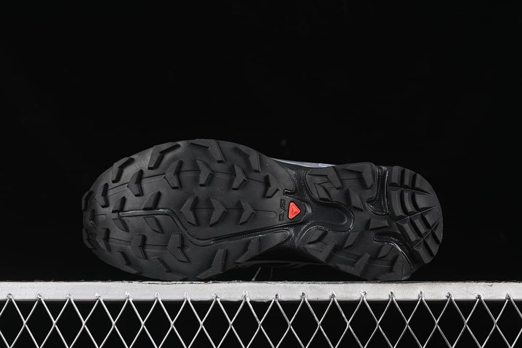 Underside view of the outsole with prominent tread lugs and a red accent.