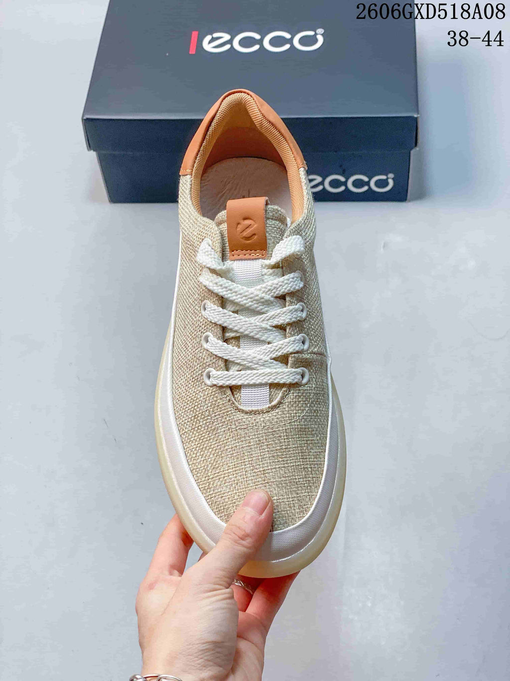 Top view of a beige lace-up sneaker with white laces and tan heel lining.