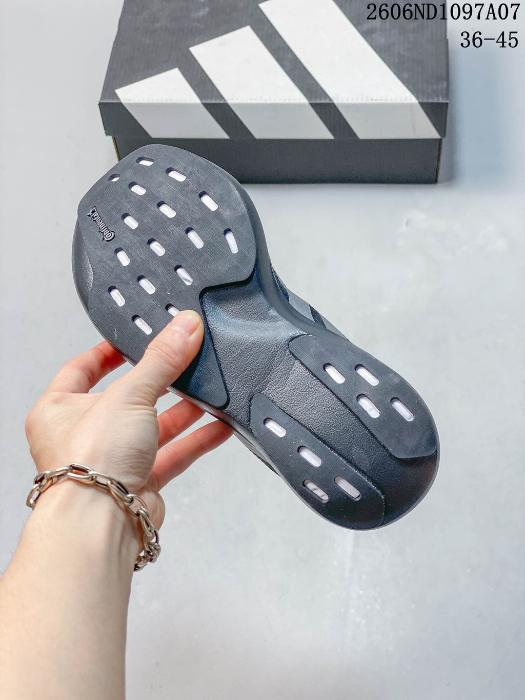 Underside of a dark gray running shoe showing its outsole and patterned openings.