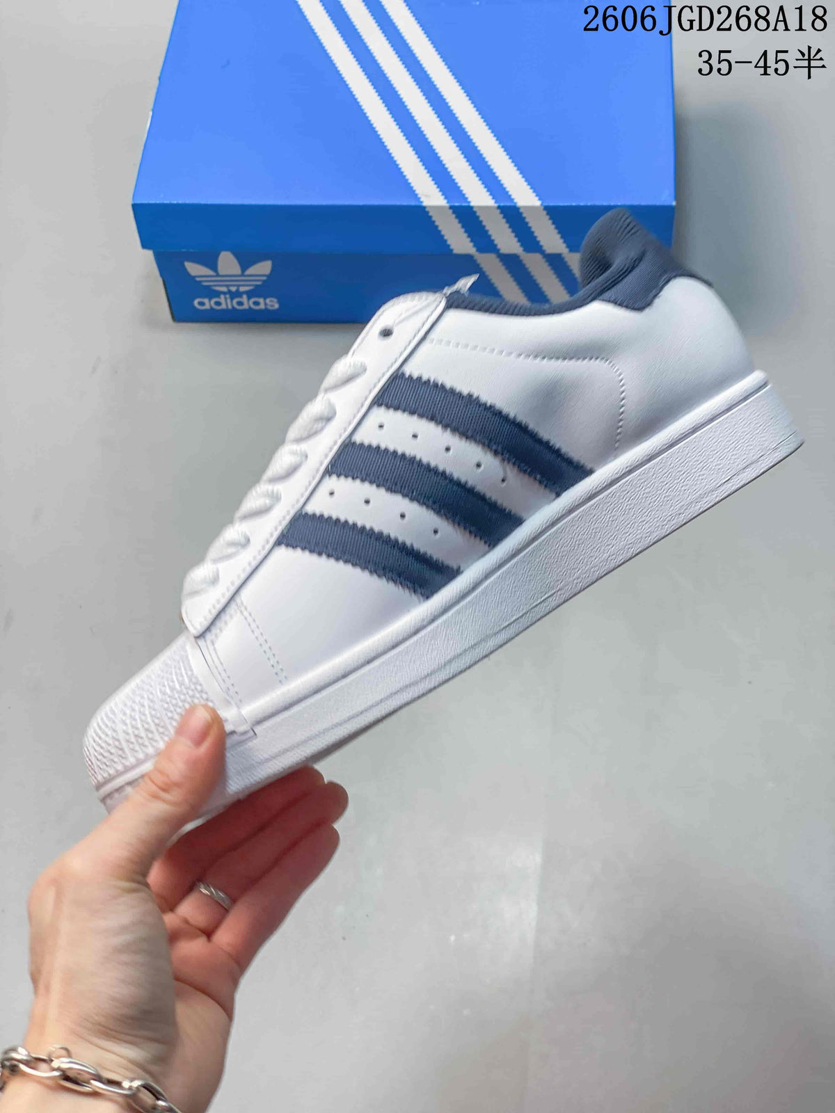 Side view showing the white upper, navy three stripes and flat sole.