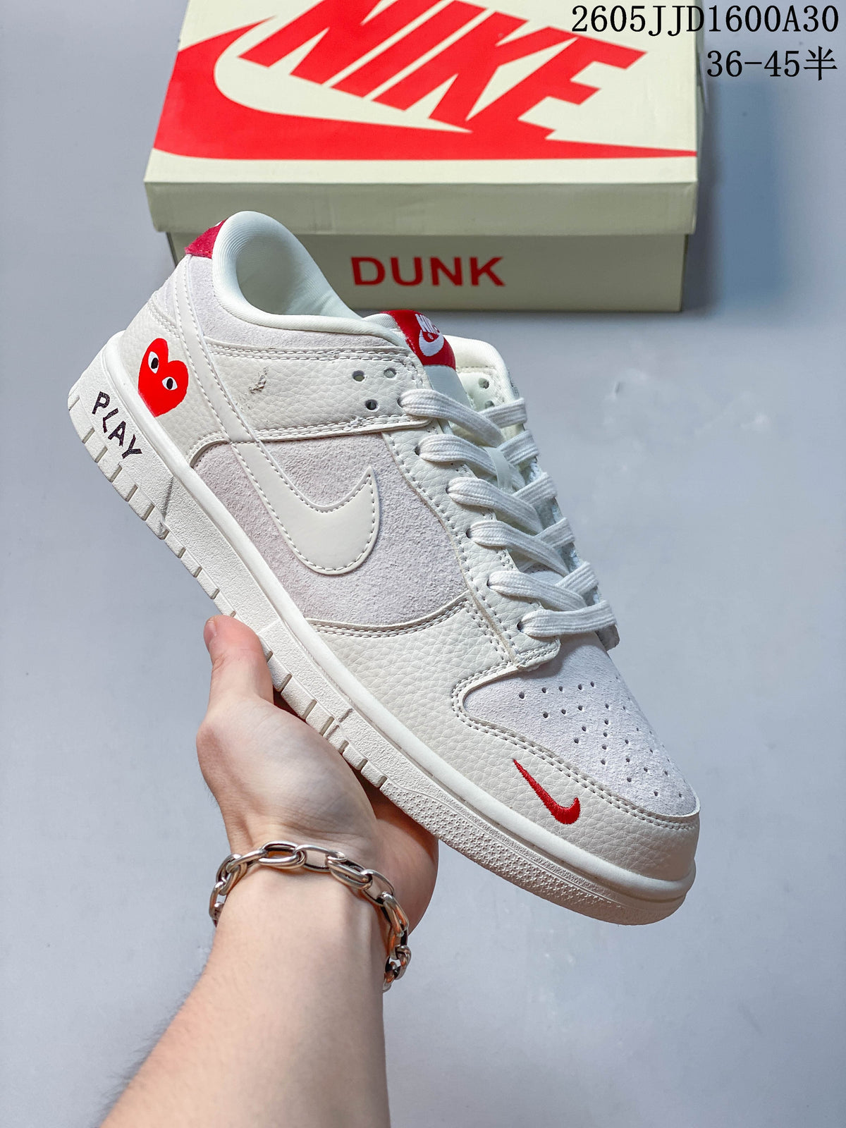 White low-top sneaker with red details and a Dunk shoe box in the background