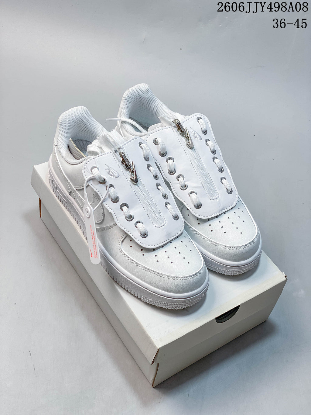 White Nike Air Force 1 ’07 Low sneakers with layered lace covers and zip details, photographed on a shoe box.