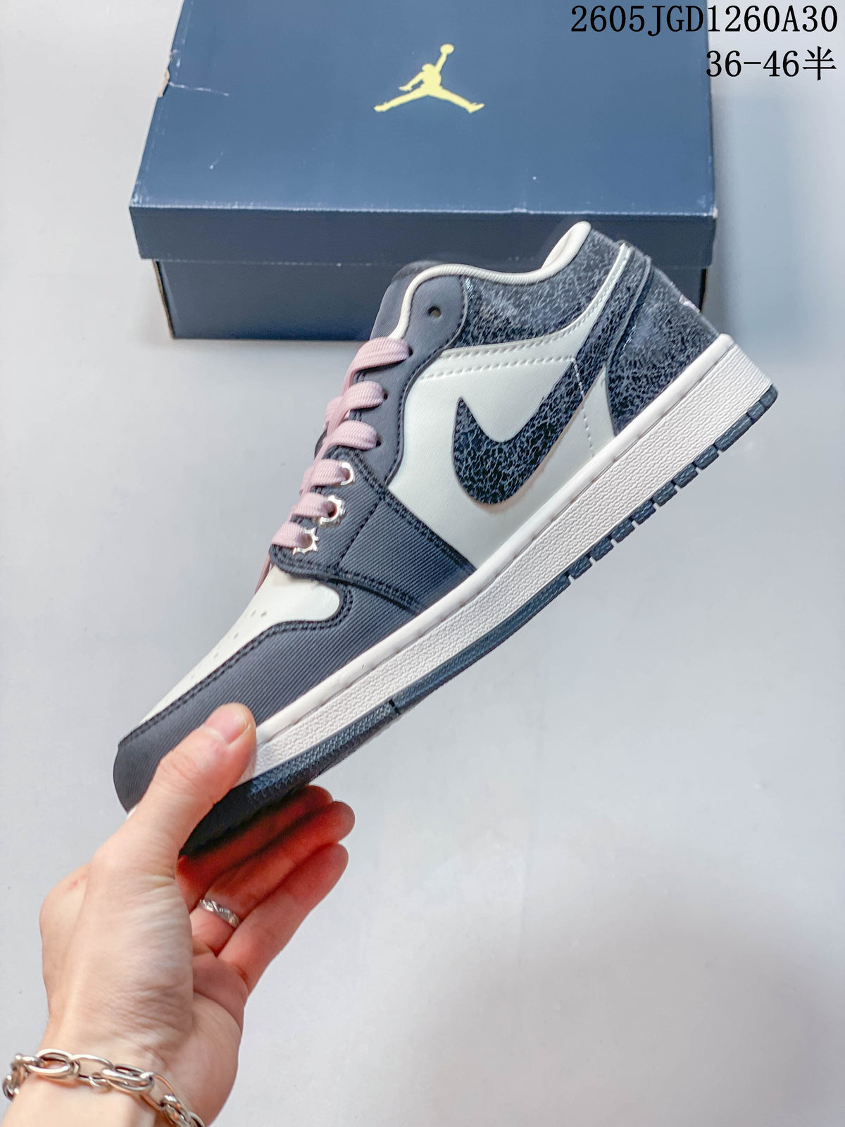 Side profile of a navy and white Jordan low-top sneaker with pink laces