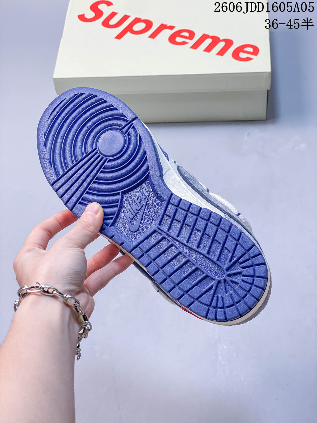 Blue outsole of a low-top sneaker with a branded box in the background