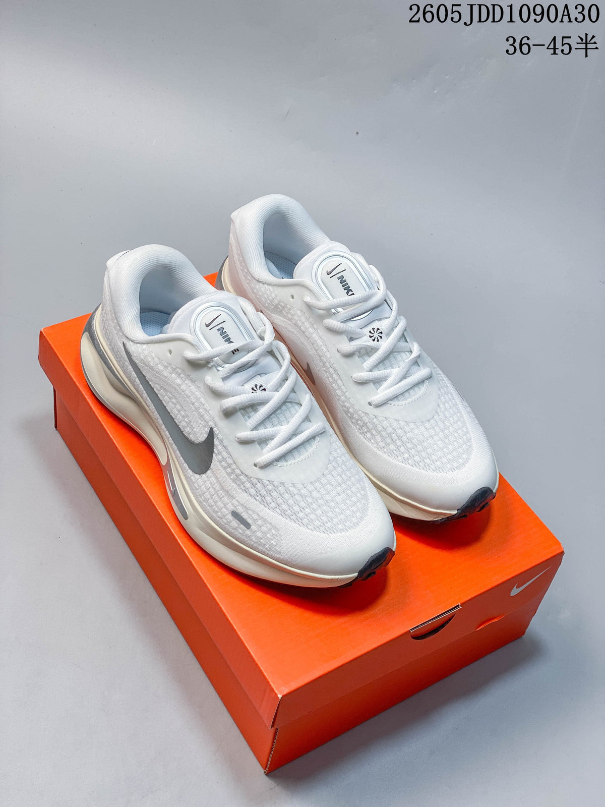 Pair of white Nike Journey Run running shoes with gray accents shown on an orange shoe box.