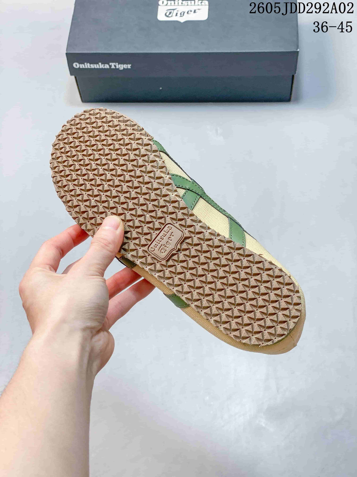 Close-up of the textured gum-brown outsole on a beige sneaker with green side stripes.