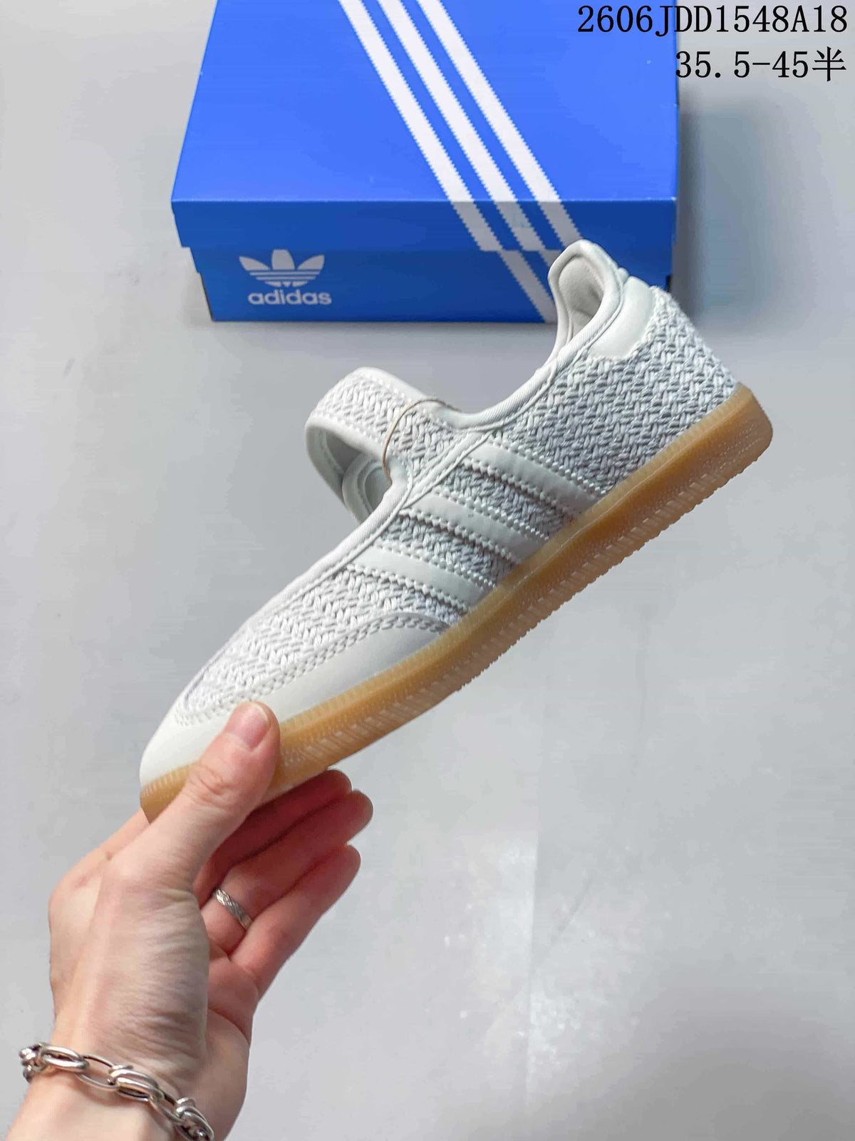 Side view of a white sneaker with three stripes, woven-look panels, and a gum-colored outsole.