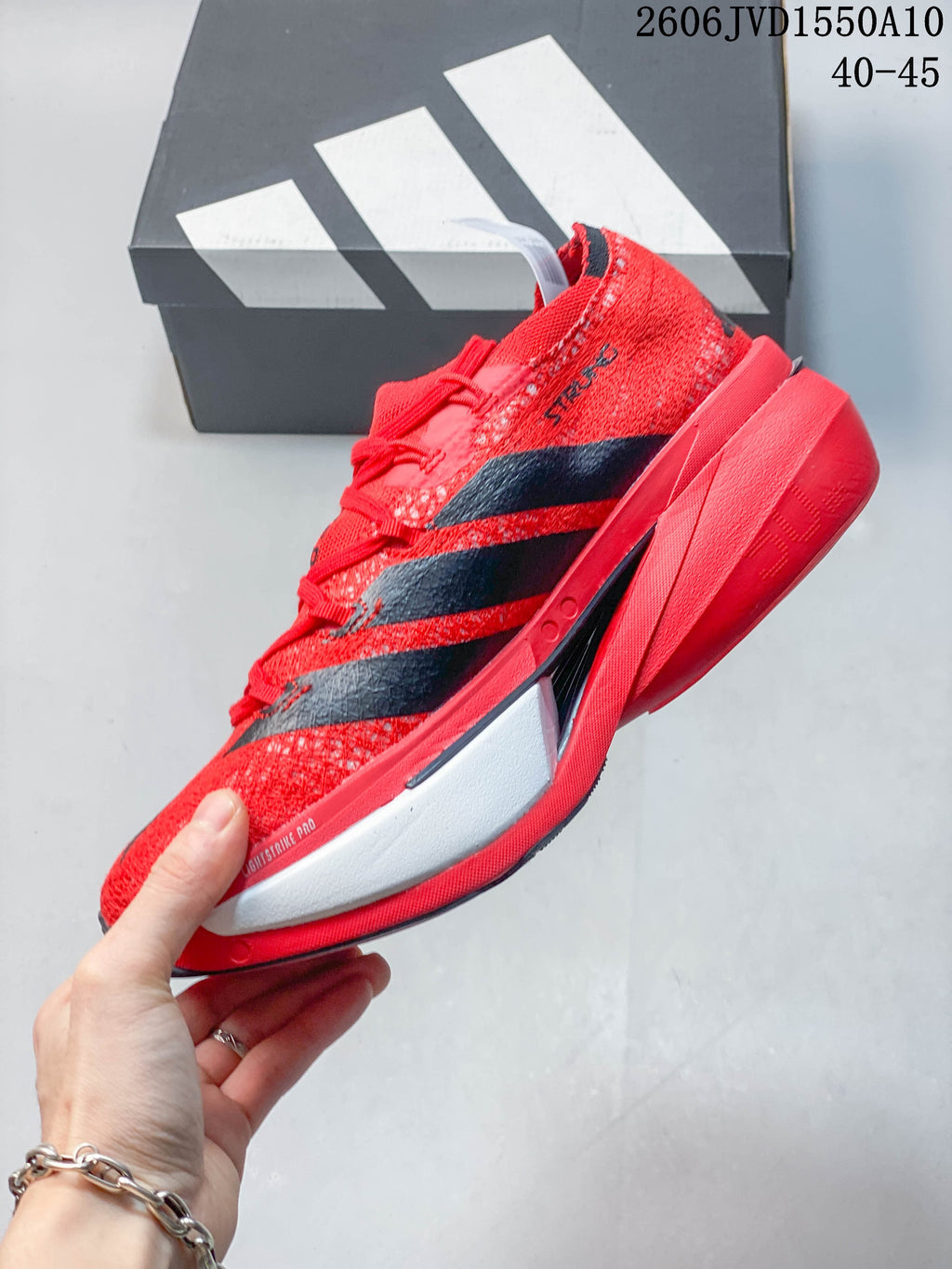 Side profile of a red adidas Adizero Prime X3 shoe with black stripes and a sculpted midsole.