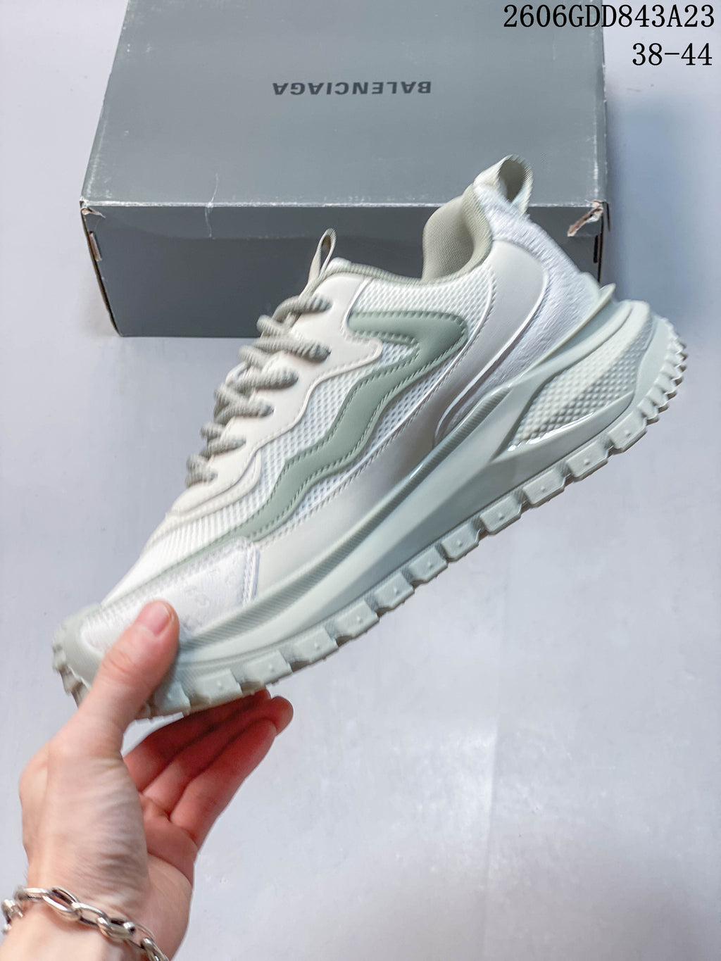 Side profile of a white sneaker with pale green accents and a chunky sole