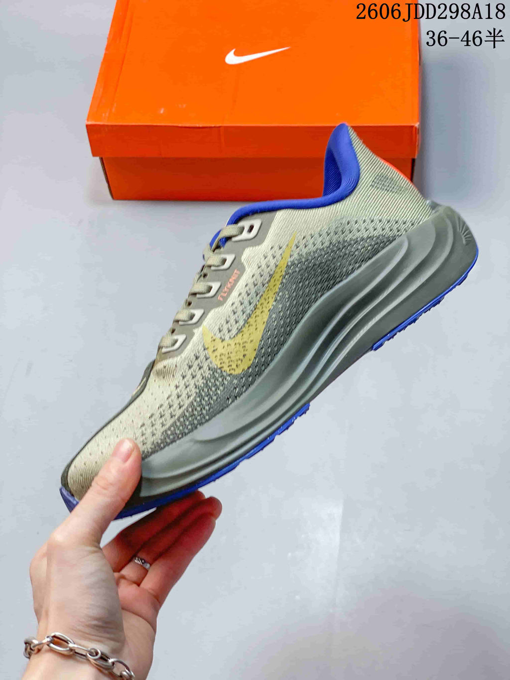 Side view of a gray-green running shoe with a blue swoosh, sculpted gray midsole, and blue outsole