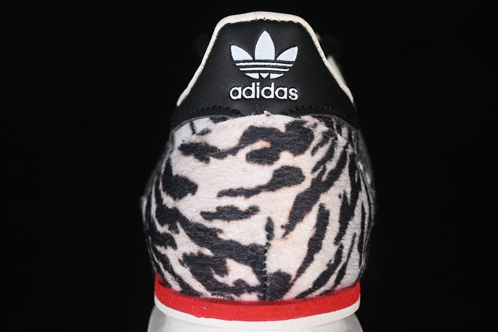 Rear view showing the black heel tab, white Trefoil logo, animal-print heel, and red accent.