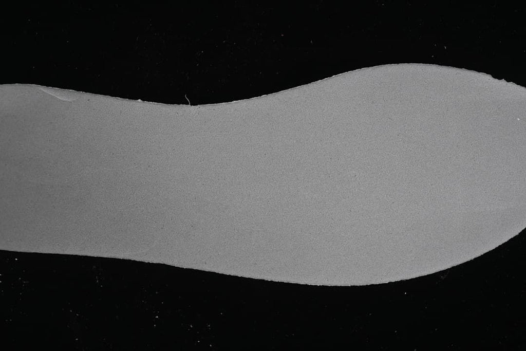 Close-up of a pale shoe-shaped surface against a dark background.