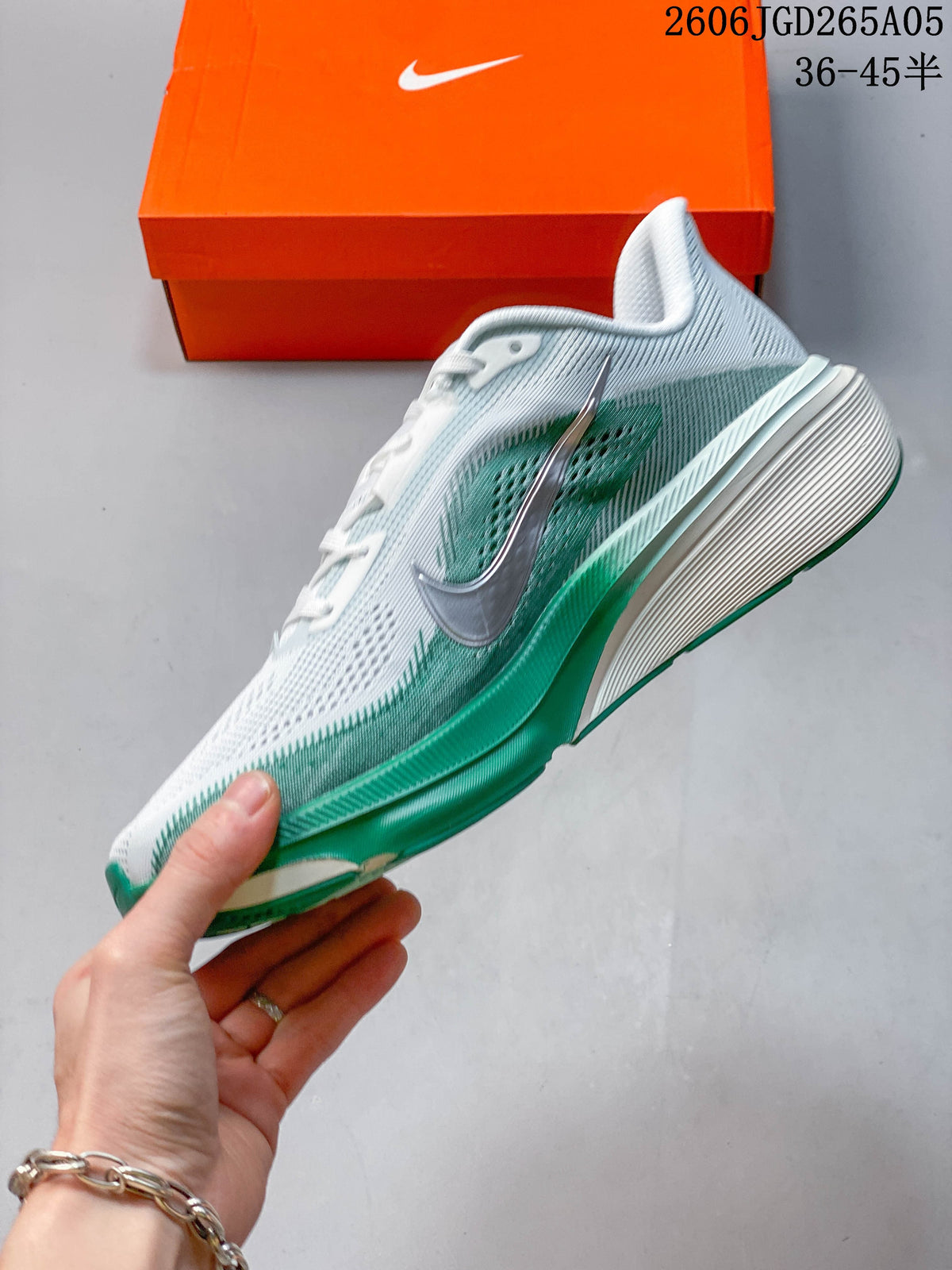 Side view of the white and green running shoe with a silver Swoosh, with size range text visible in the image
