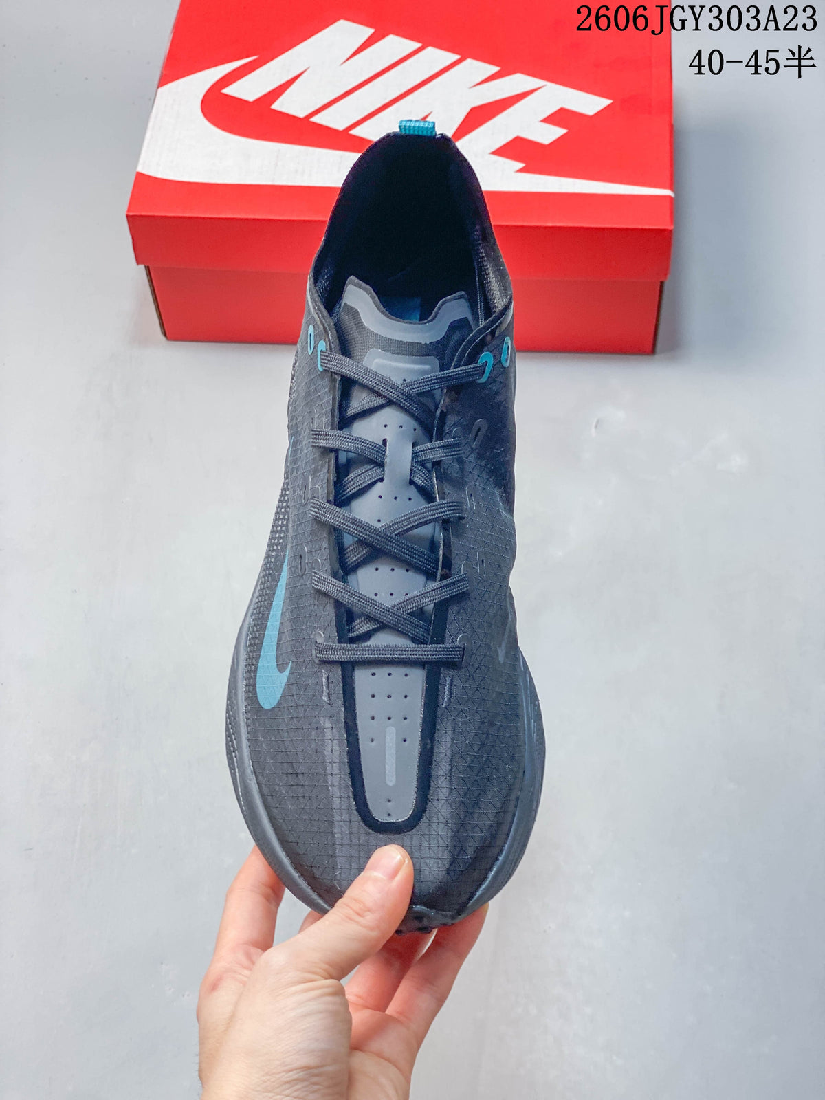 Top view of a charcoal Nike Ava Rover shoe with blue lace eyelets and branding