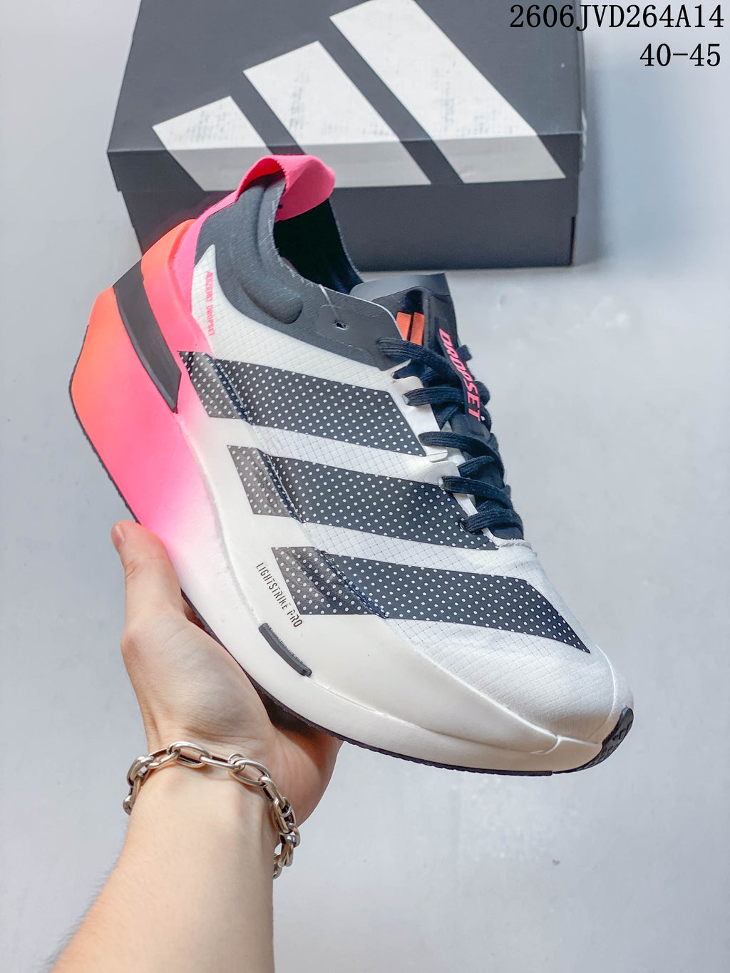 Side view highlighting the white upper, dark panels, and pink-orange heel and sole.