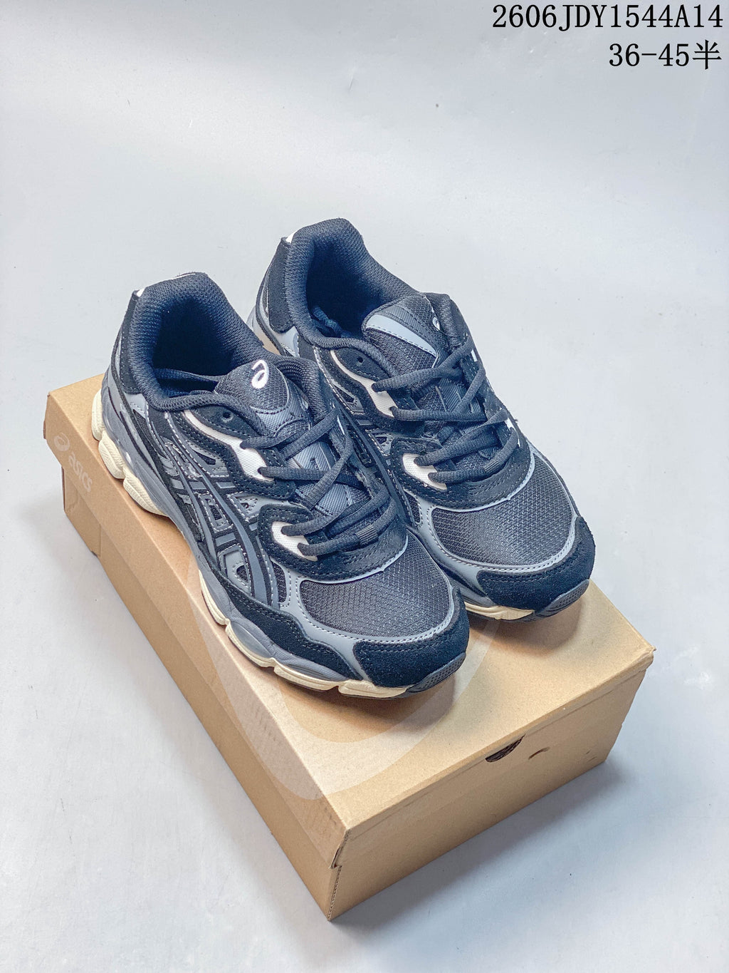 Pair of navy and gray ASICS GEL-NYC sneakers shown from above on a shoebox