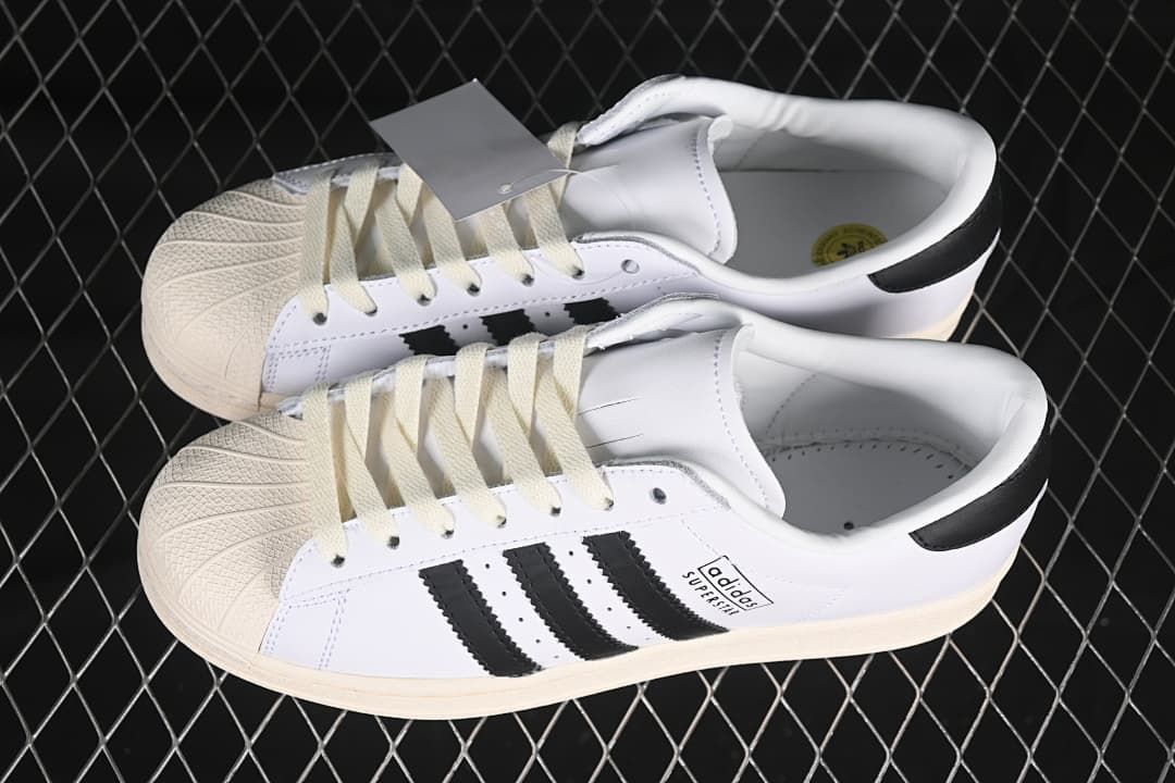 Pair of white and black Adidas Superstar sneakers with cream details