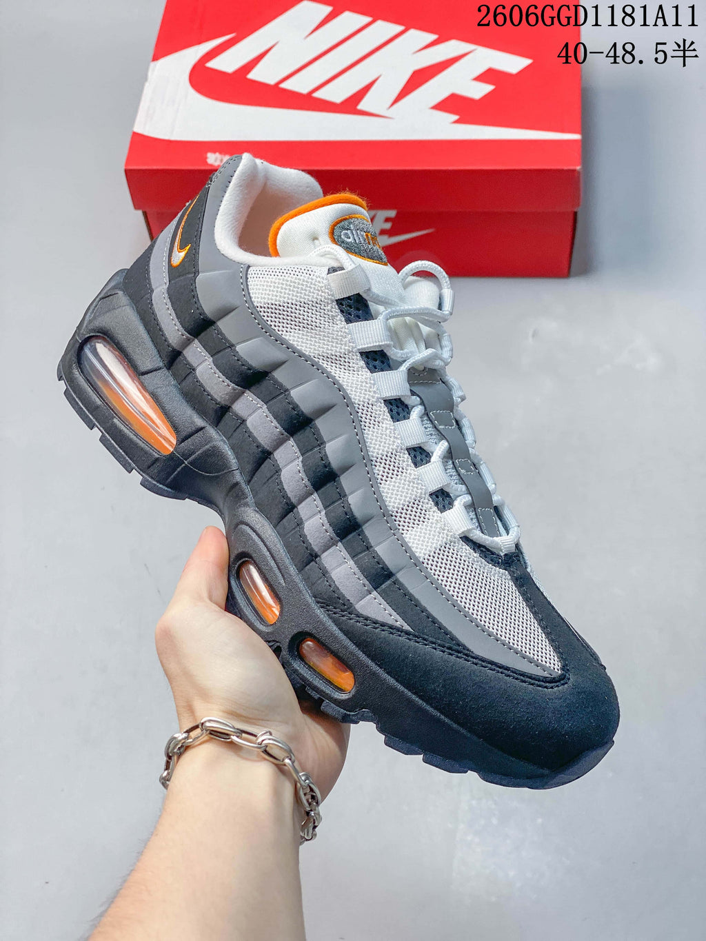 Angled side view of a Nike Air Max 95 OG sneaker with gray and navy panels and orange accents