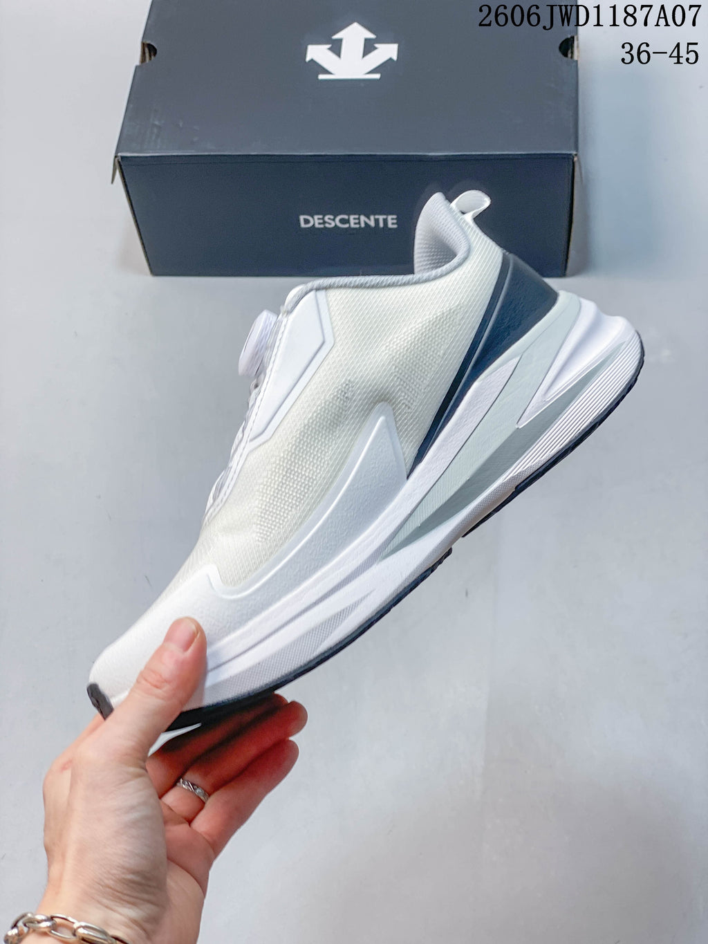 Side profile of the white DESCENTE low-top shoe with dark heel detailing.