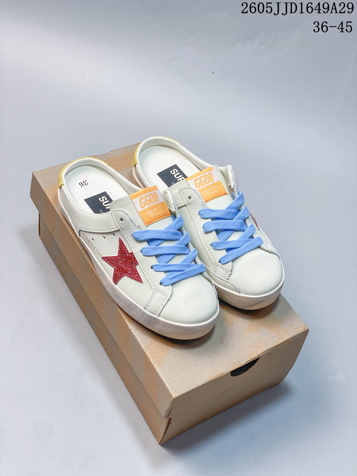 Pair of white low-top sneakers with blue laces, red glitter side stars, and yellow heel accents