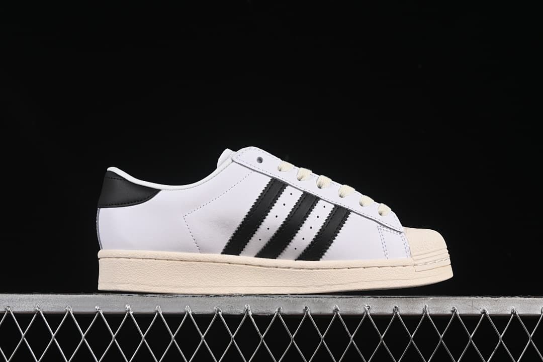 Side profile of the white sneaker with black stripes and cream-colored sole