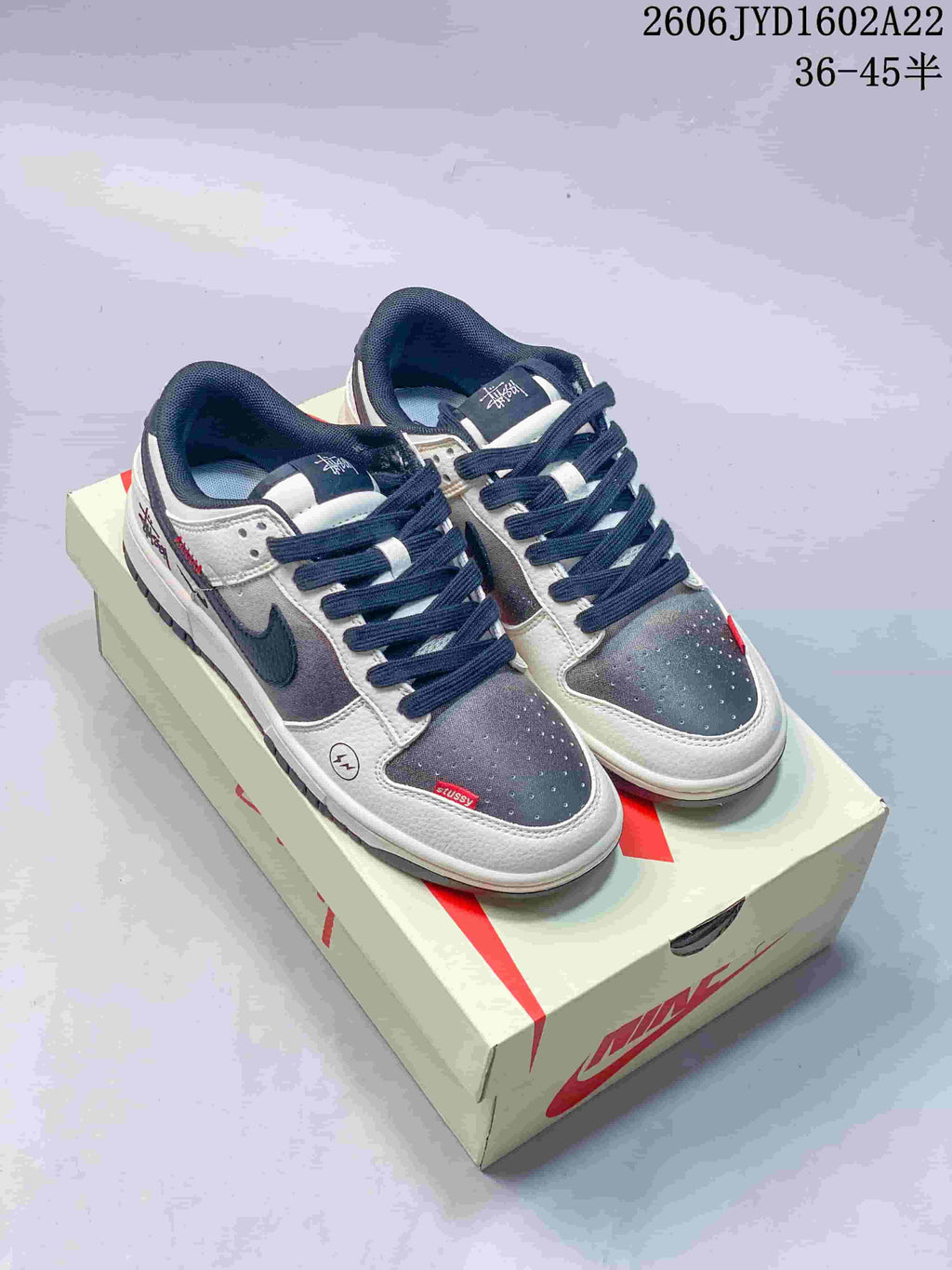 Pair of beige, gray, navy and red low-top sneakers displayed on a shoe box