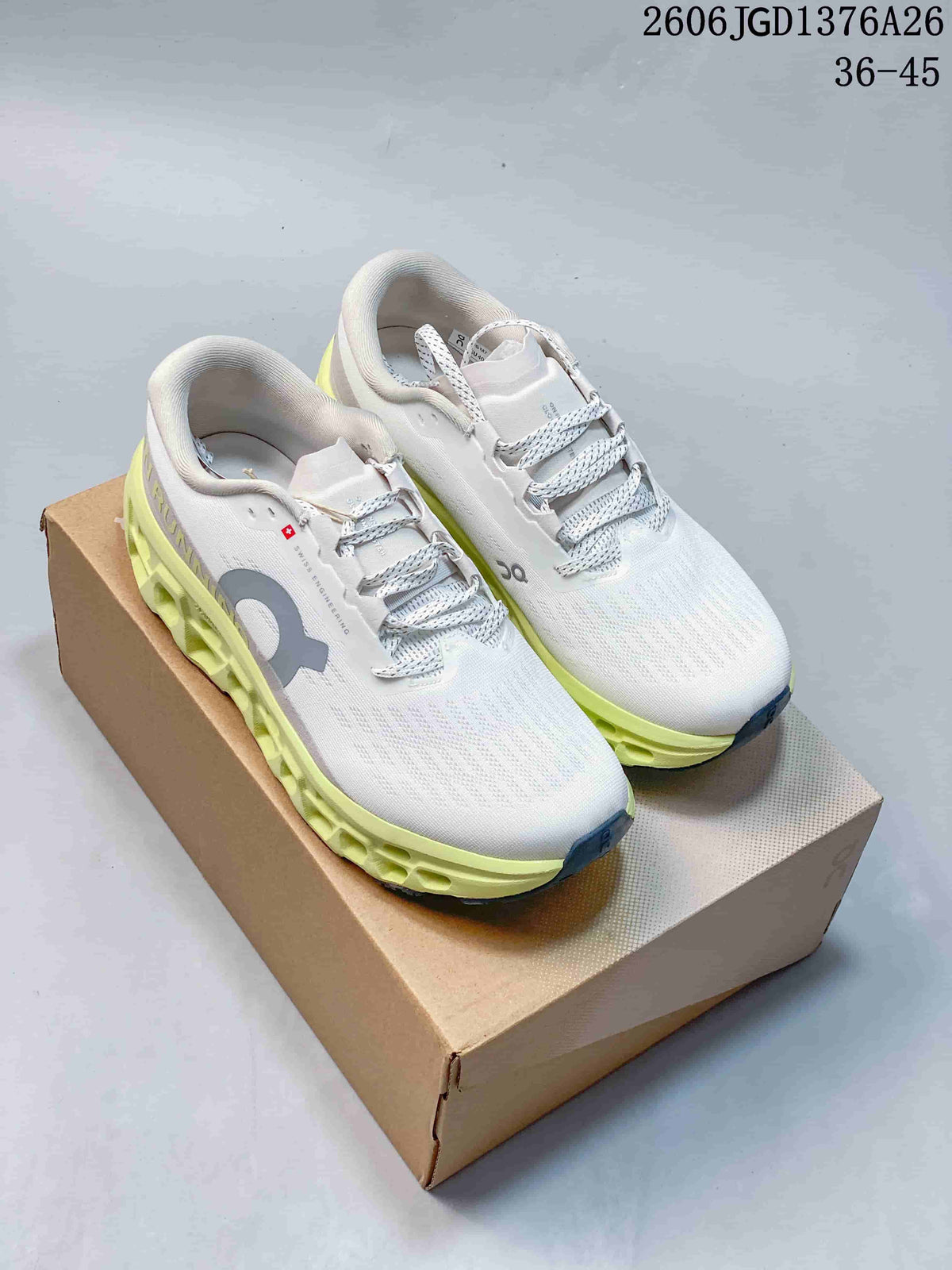 White On Cloudmonster 3 shoes with lime accents, shown from above on a box.