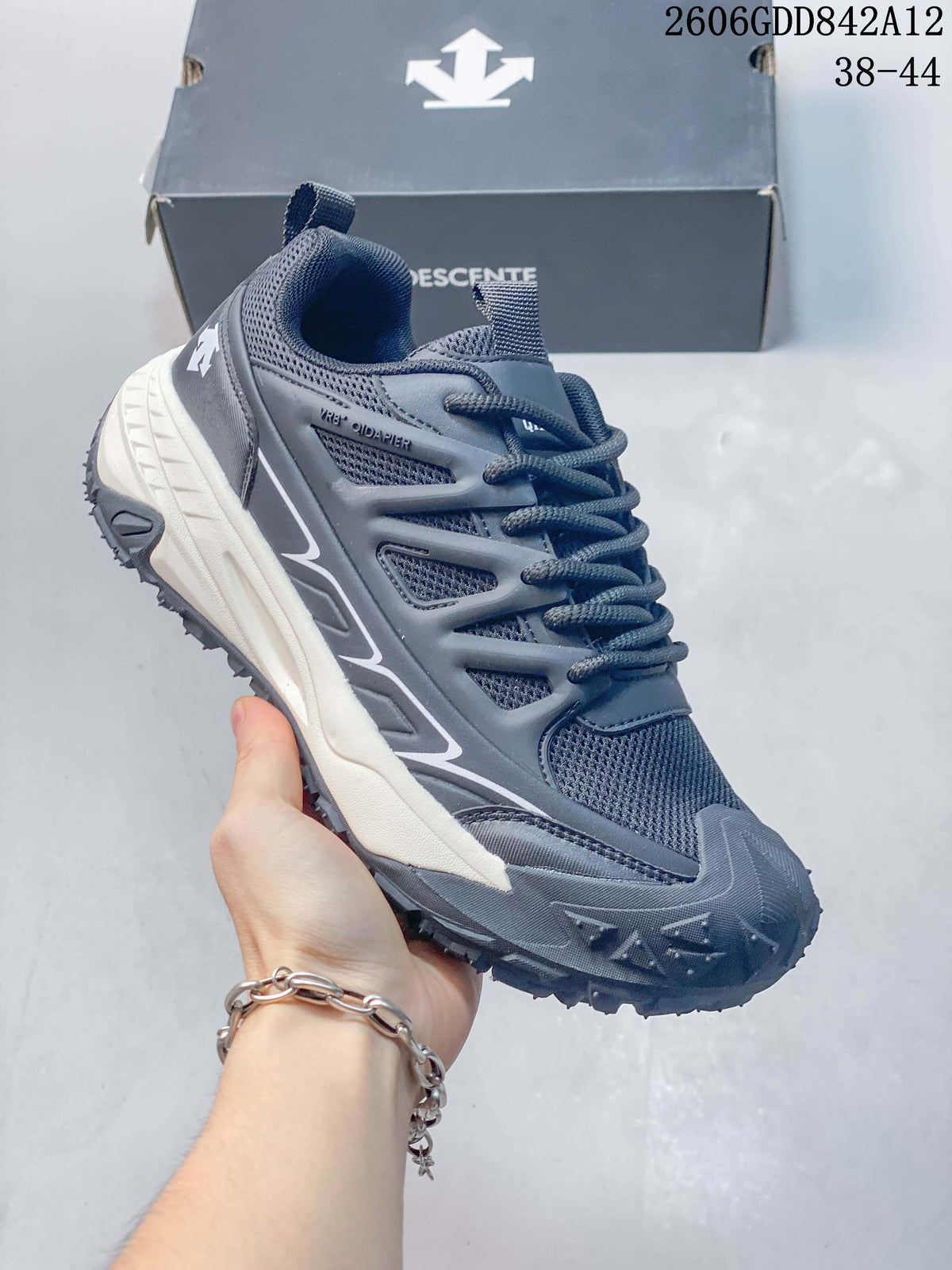 Angled side view of a gray DESCENTE sneaker with a rugged outsole and contrasting midsole.