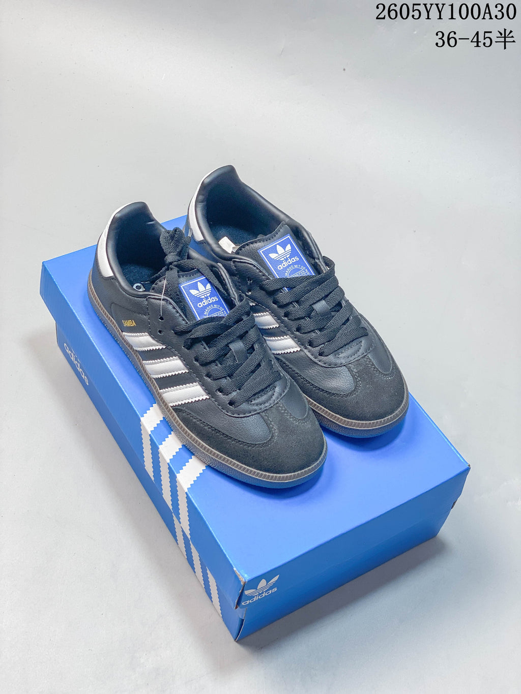 Dark grey Adidas Samba OG low-top sneakers with light side stripes on a blue box