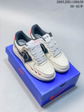 White low-top sneakers with dark patterned side panels, red accents, gray laces, and a blue box