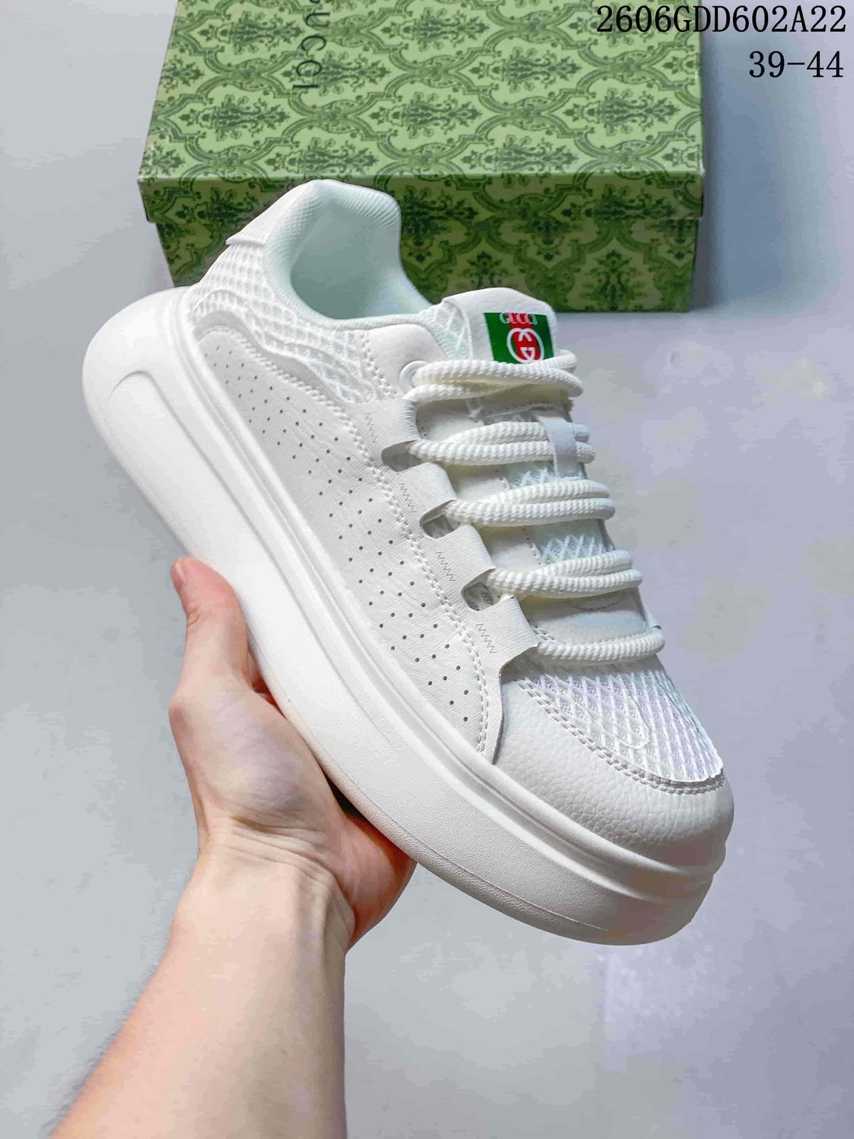 Side view of a white sneaker with perforated panels and a thick white sole.