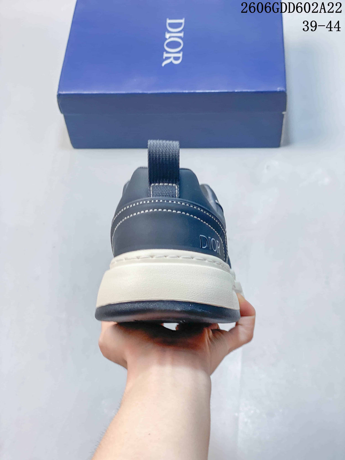 Rear view of a navy sneaker with contrast stitching and a Dior mark on the heel