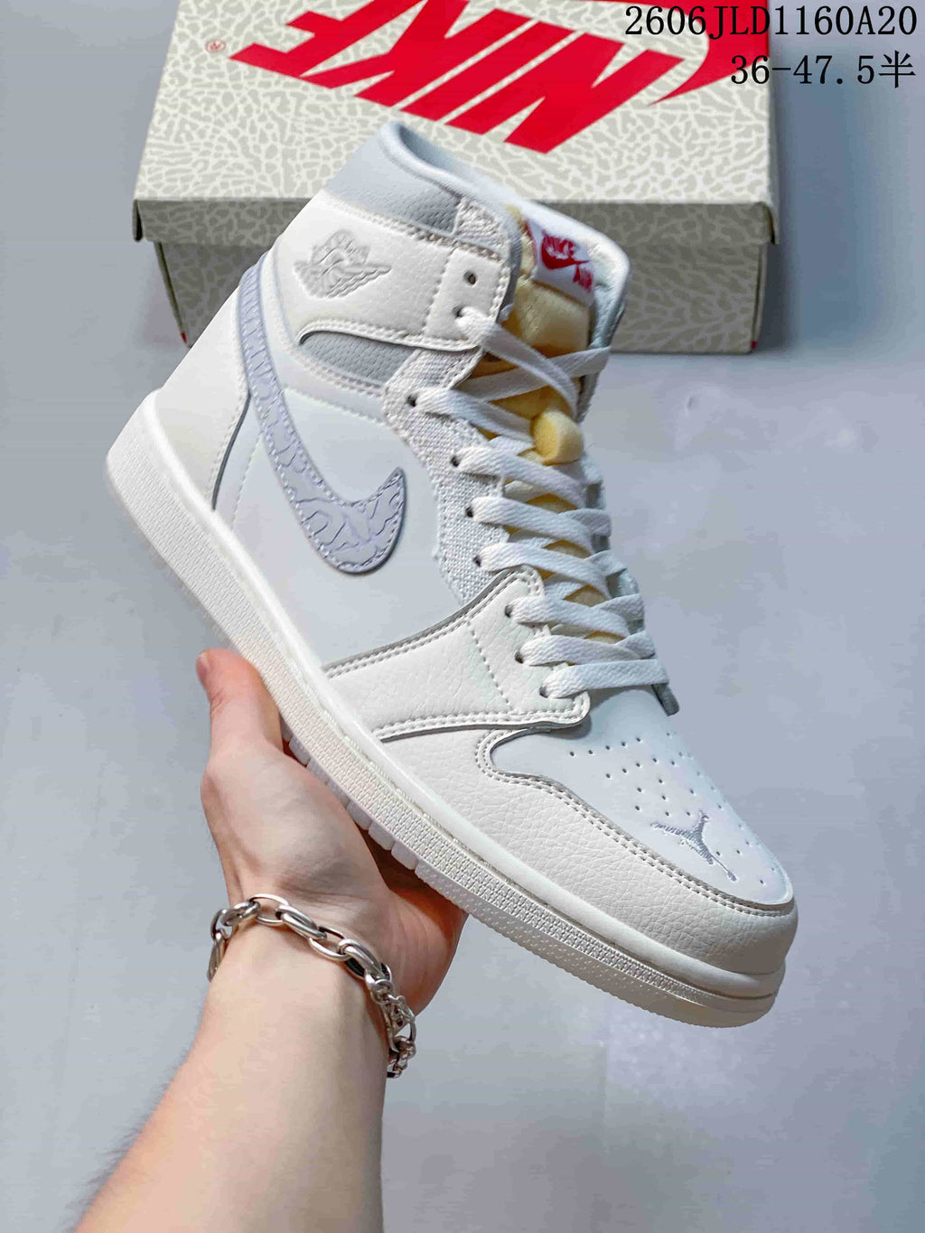 Side view of a white Jordan 1 high-top sneaker with pale gray accents