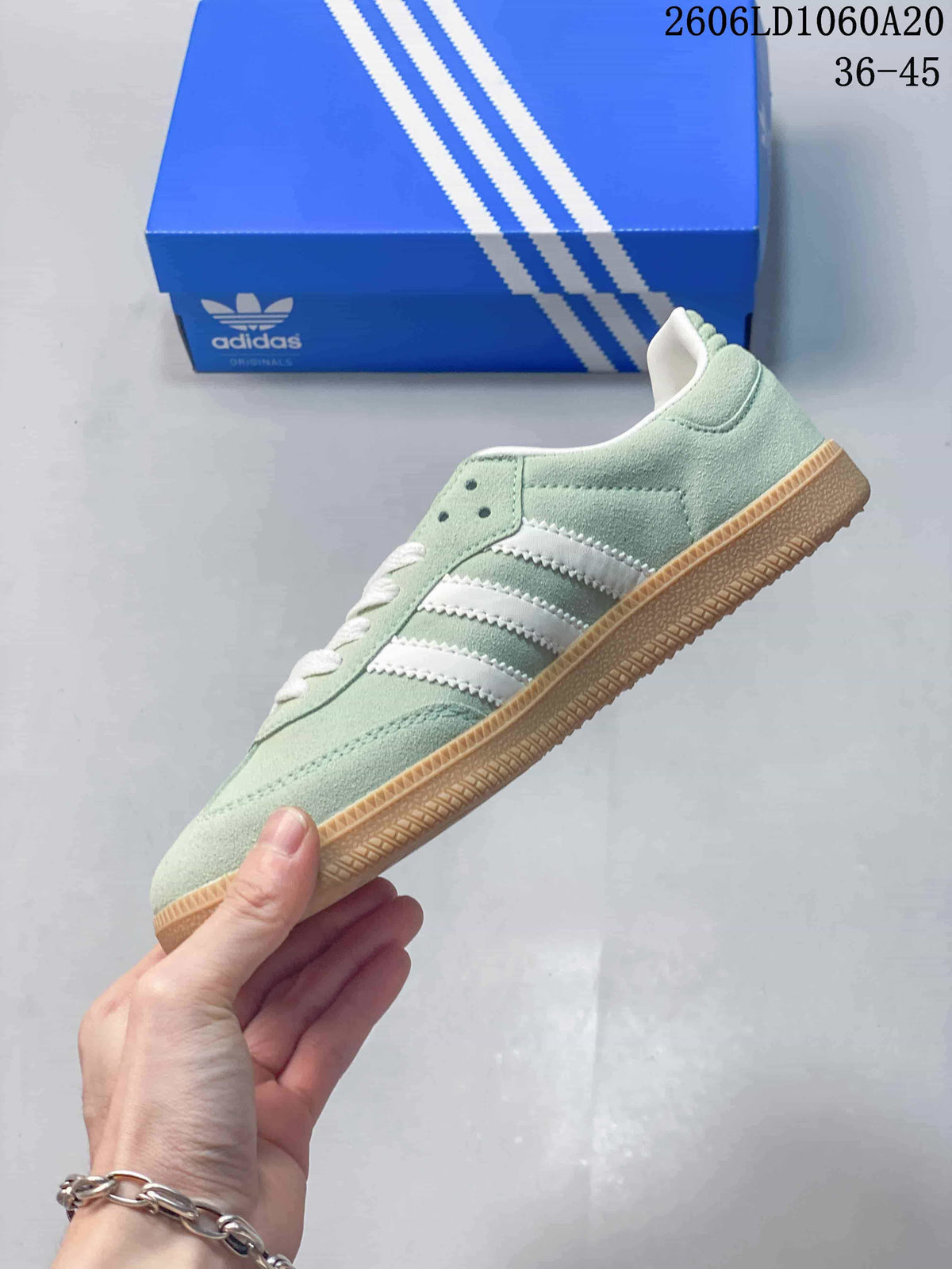 Side view of a pale green low-top sneaker with white stripes and a gum-colored sole.
